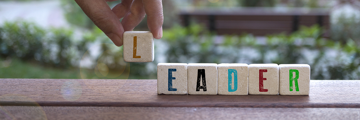 A hand putting the L on the word leader spelled out in blocks.