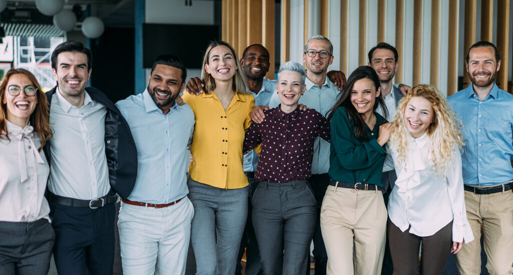 A group of diverse colleagues hugging and celebrating in an office.