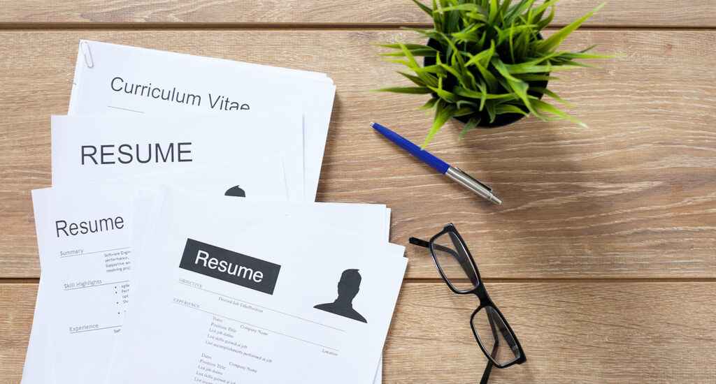 Resume applications on desk ready to be reviewed.