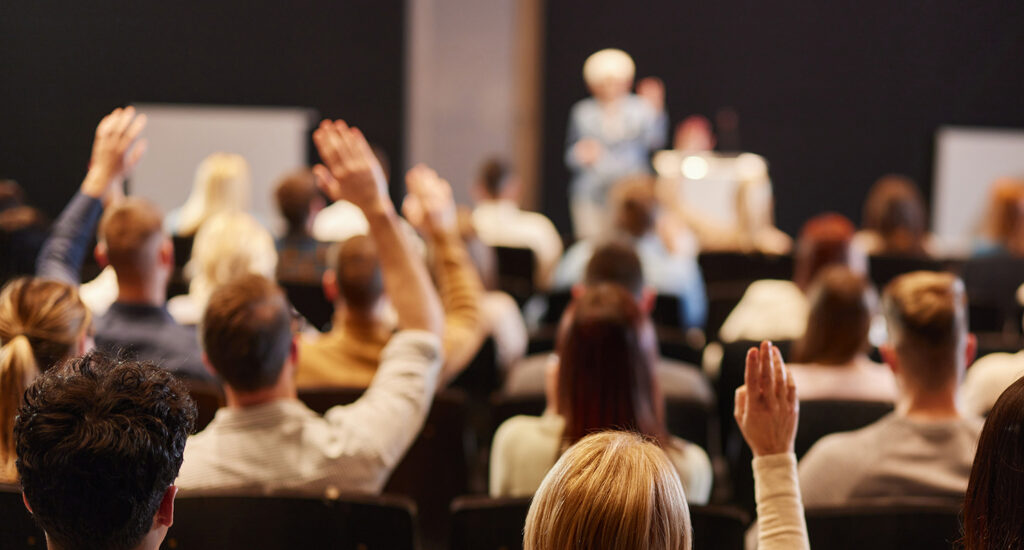 Audience engaged with hands raised.