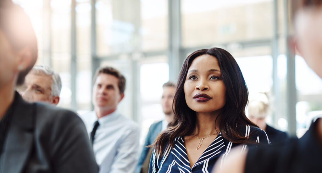 Diverse group of professionals listening to a presentation in an office.