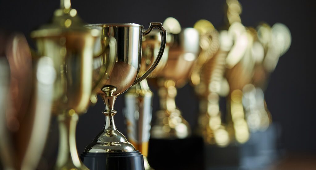 Row of gold trophies of different sizes.